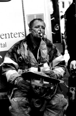 An exhausted hero firefighter receives oxygen and water